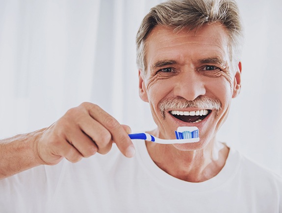 Man with dentures brushing his teeth