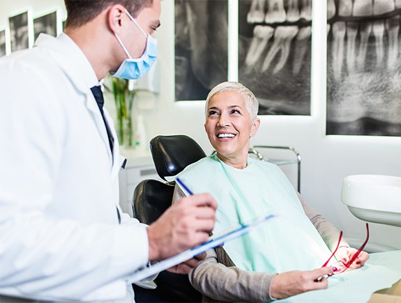 Dentist taking notes while talking to patient