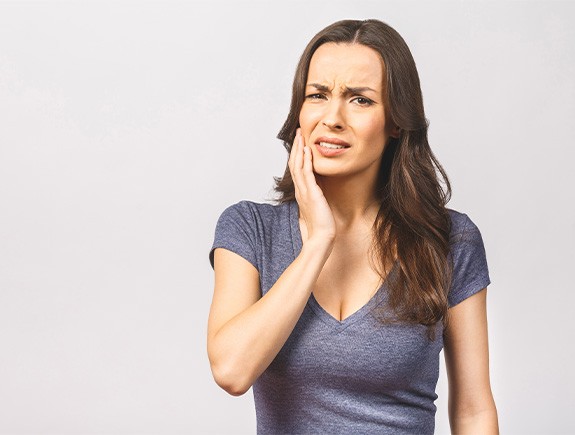 Grimacing woman touching the side of her face