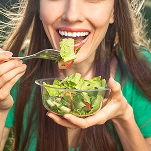 Woman in green shirt eating a salad