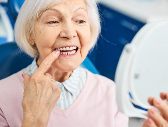 Senior woman checking her smile in a handheld mirror