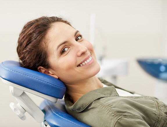 Woman leaning back in dental chair and smiling