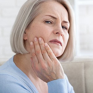 Senior woman rubbing her jaw in discomfort