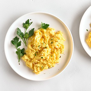 Plates with scrambled eggs on white table